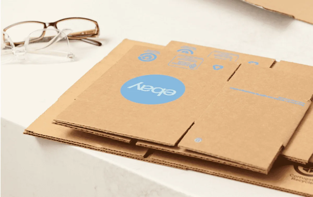 Stacked brown shipping boxes printed with the eBay logo on a white surface